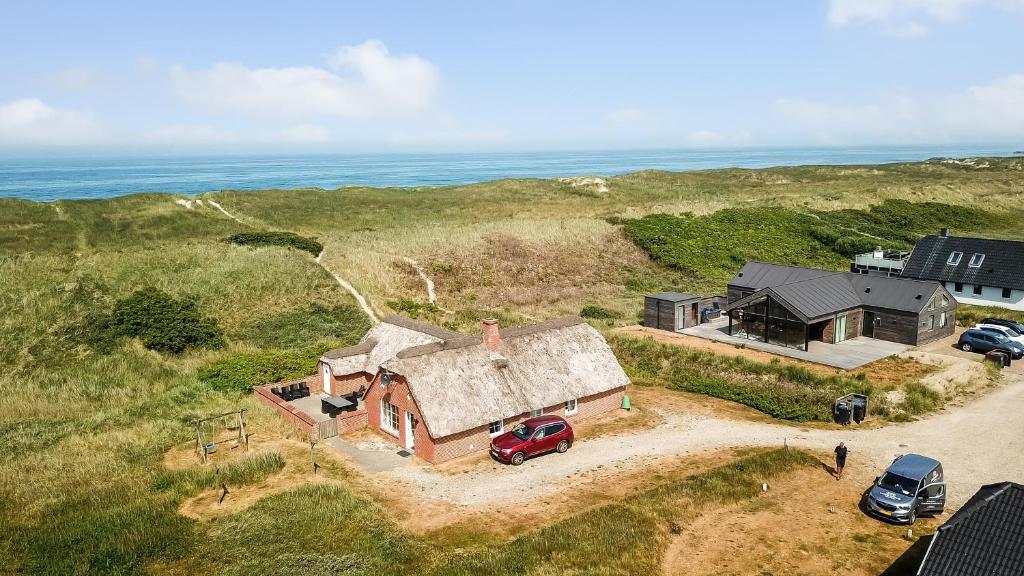 una vista aérea de una casa con un coche aparcado delante en Thatched house with spa and pool by the sea - SJ67 en Harboør