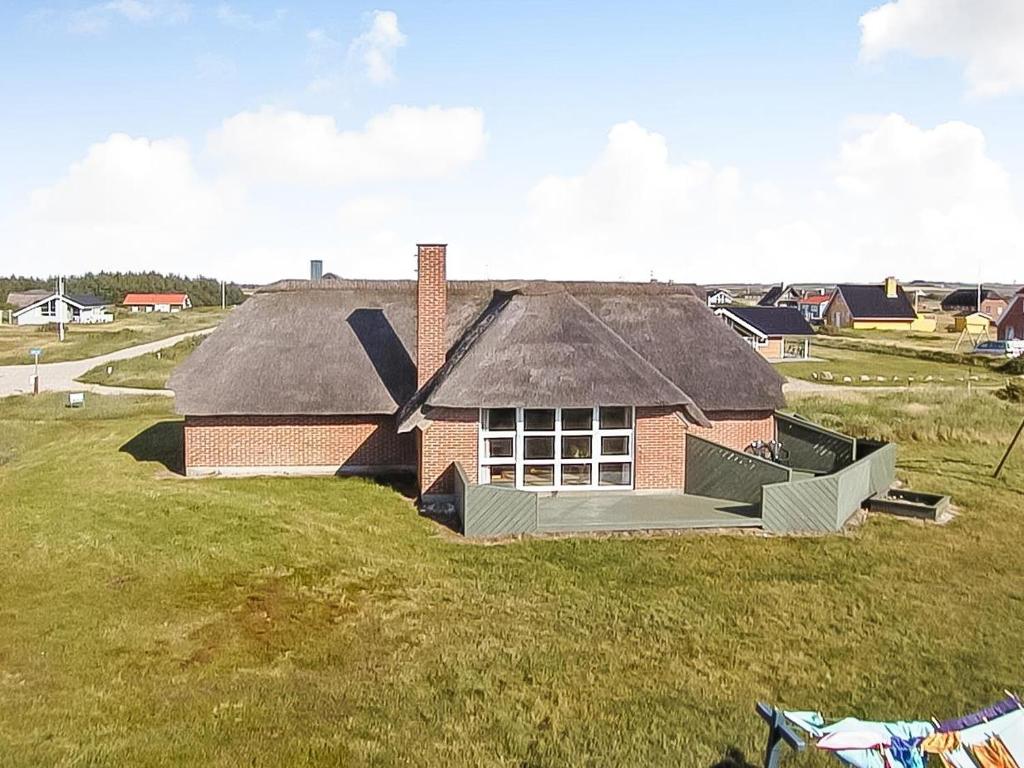 una casa sentada en la cima de un campo de hierba en Charming thatched stone house by the sea - SJ241 en Harboør