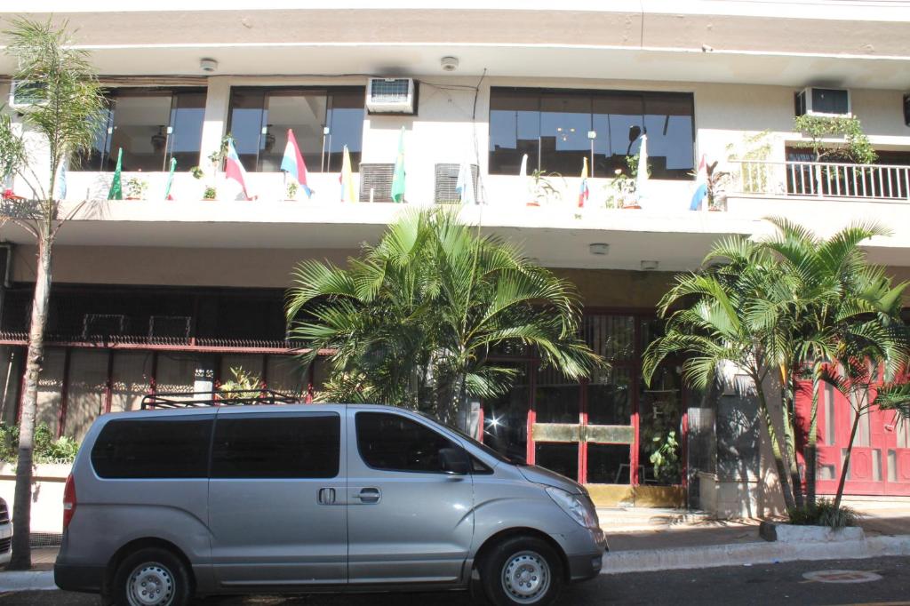 una furgoneta estacionada frente a un edificio con palmeras en Gran Hotel Parana, en Asunción