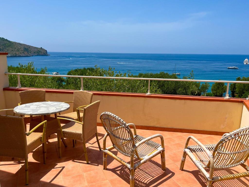 balcón con mesa, sillas y vistas al océano en NaturAmare Apartments Palinuro, en Palinuro