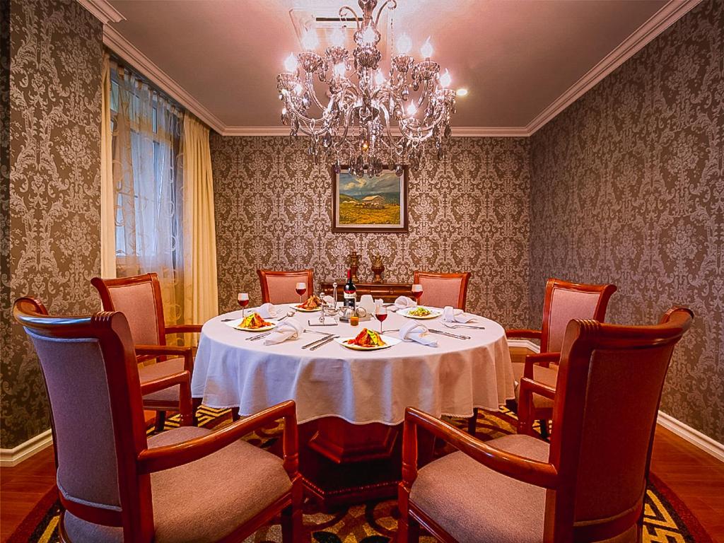 a dining room with a table and chairs and a chandelier at Buudai hotel in Darkhan
