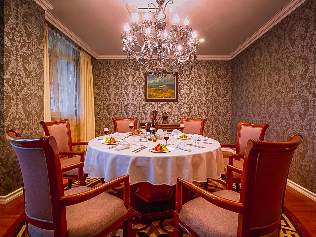 een eetkamer met een tafel en stoelen en een kroonluchter bij Buudai hotel in Darhan