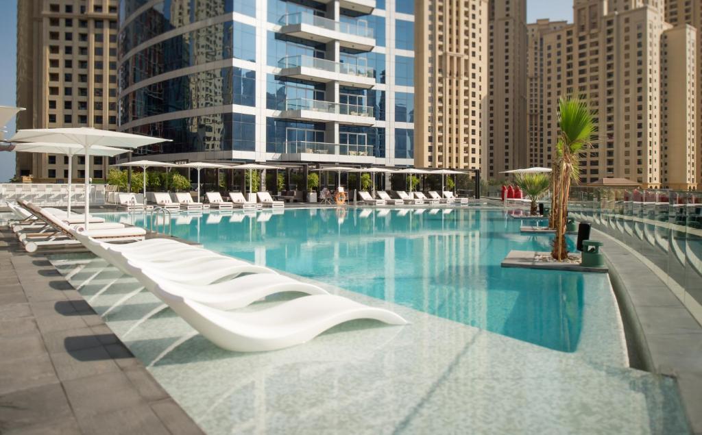 a large swimming pool with white chairs and umbrellas at InterContinental Dubai Marina by IHG in Dubai