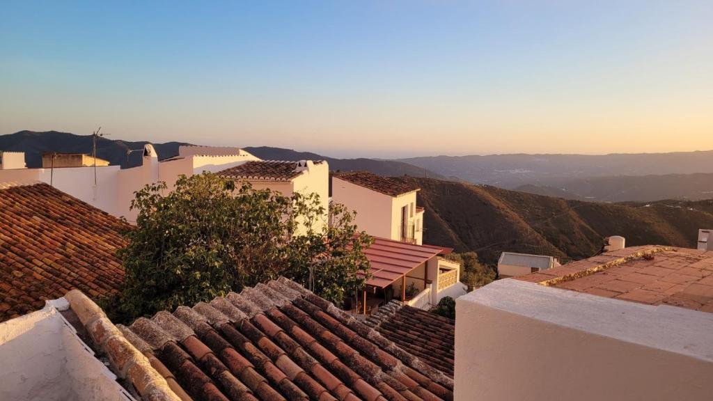 einen Blick auf die Dächer von Gebäuden mit Bergen im Hintergrund in der Unterkunft Casa María Martillo in Canillas de Aceituno