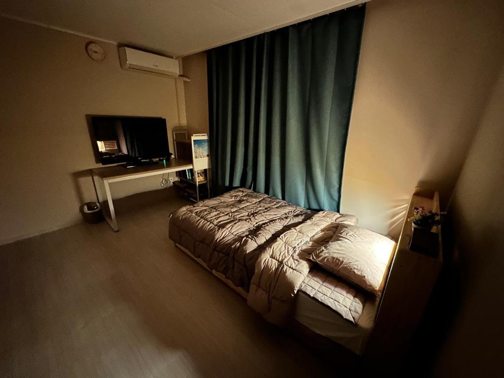 a bedroom with a bed and a window with a television at Memory - Internationals Only in Daegu