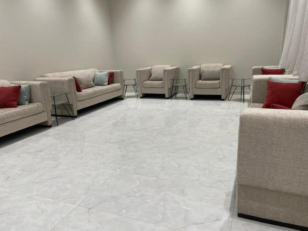a waiting room with couches and chairs on a tile floor at شالية الفهد in Bawḑah