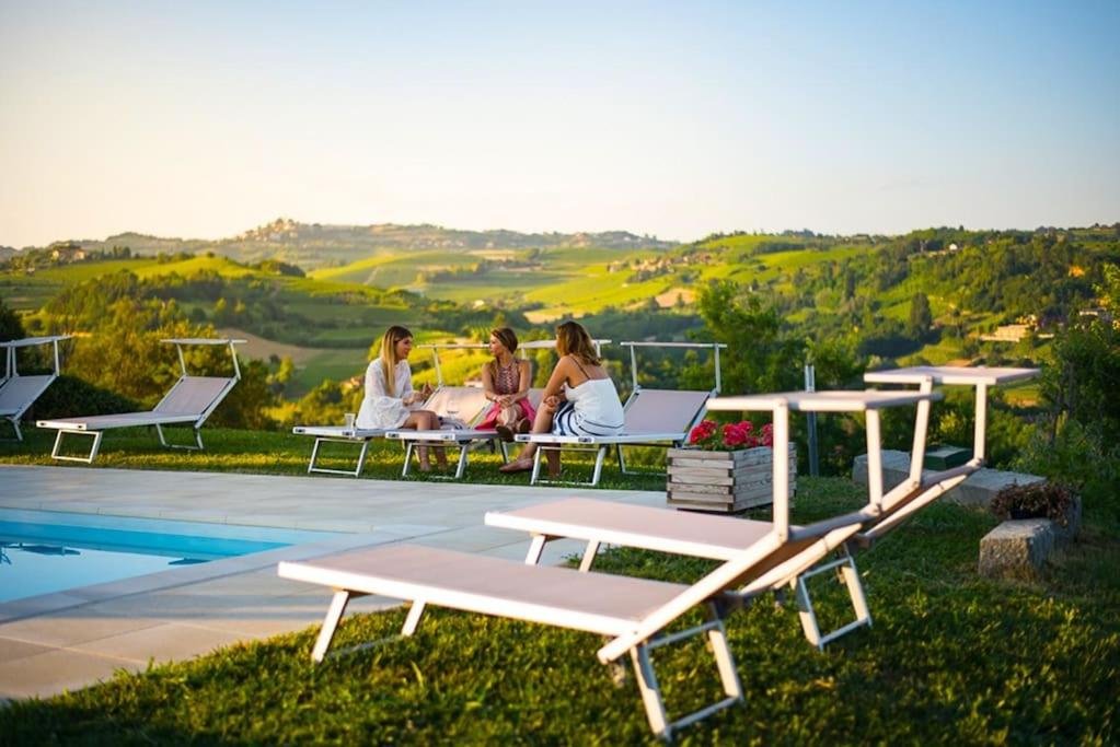 eine Gruppe von Frauen, die auf Liegestühlen am Pool sitzen in der Unterkunft CONFINEDEISANTI Bed&Breakfast in Moriondo Torinese