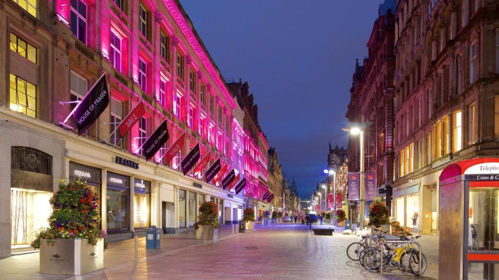 eine Stadtstraße in der Nacht mit rosa Lichtern an Gebäuden in der Unterkunft Central Gem 1 Bed Flat City Centre in Glasgow