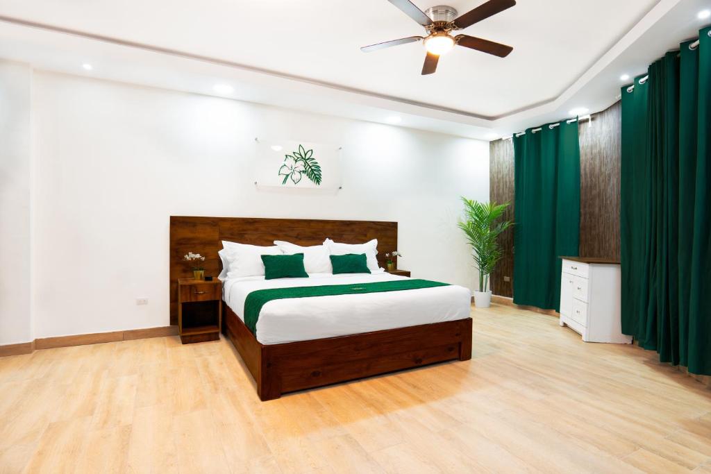 um quarto com uma cama grande e cortinas verdes em Jardin Colonial Boutique Hotel em Santo Domingo