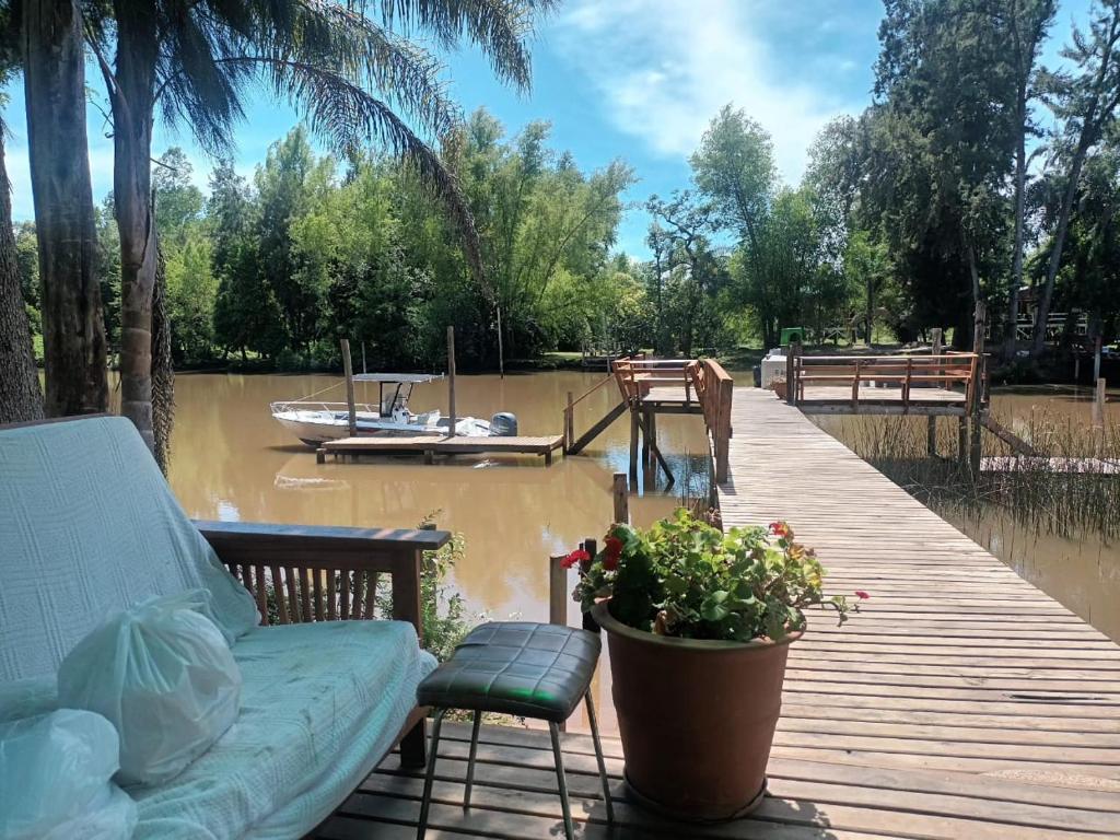 a deck with a couch and a boat on a river at Lodge Gloria in Dique Luján