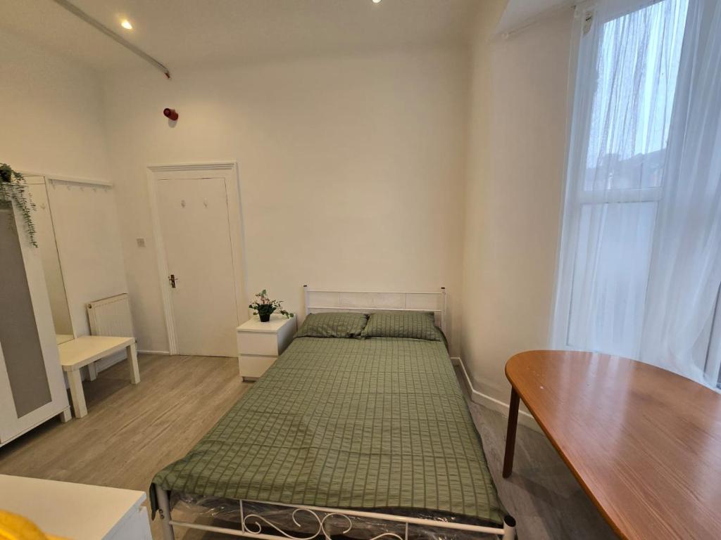 a bedroom with a bed and a table and a window at RELAKS LETTINGS in London