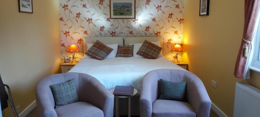 a bedroom with a bed and two chairs at Ornum House in Beauly