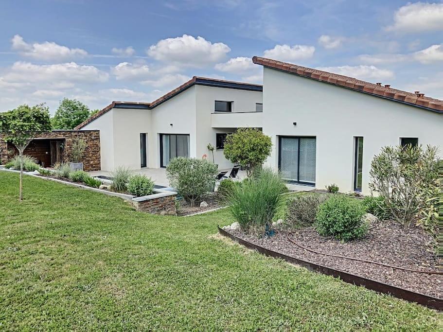 une maison blanche avec une cour devant elle dans l'établissement Magnifique Villa Piscine, Salle Cinema Est Toulouse, à Sainte-Foy-dʼAigrefeuille