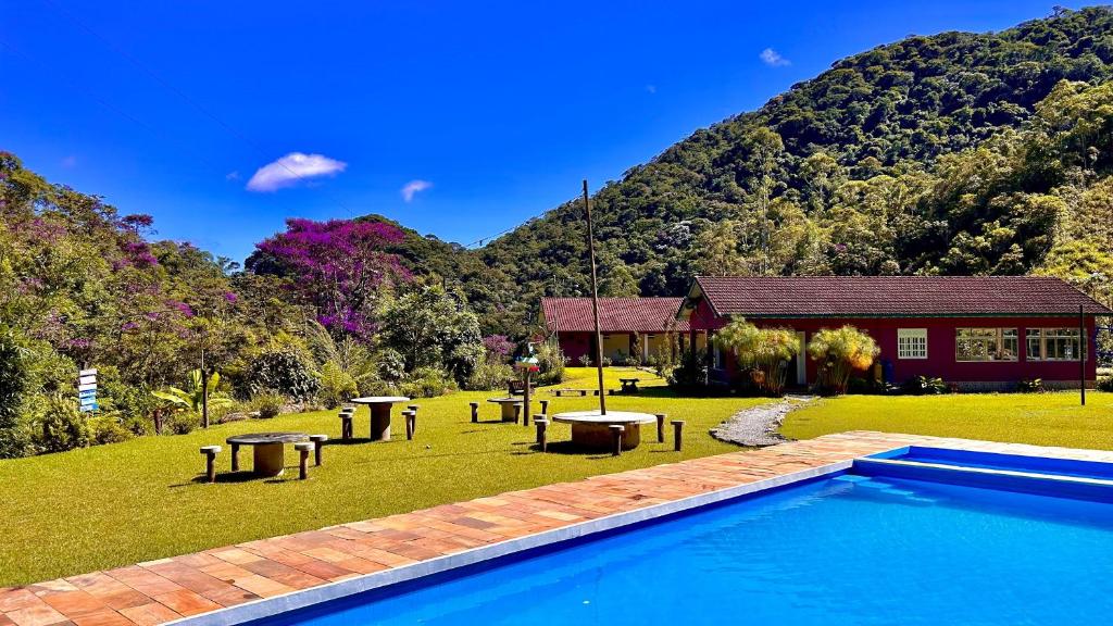 a swimming pool in front of a house with a mountain at Sítio Toca da Toca in Lumiar