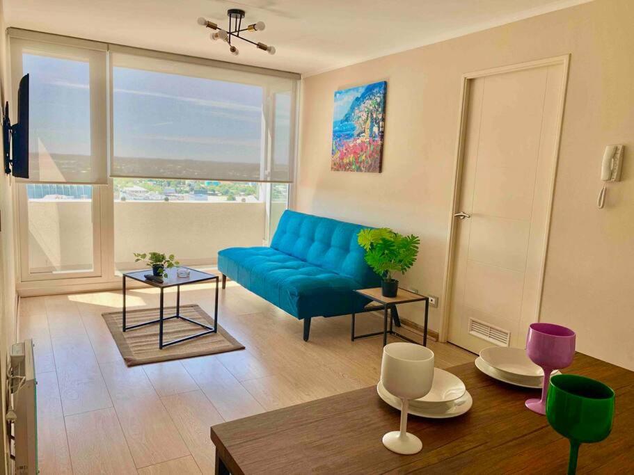 uma sala de estar com um sofá azul e uma mesa em Departamento 3 piezas Centro Chillan - Parking - Vista - Factura em Chillán