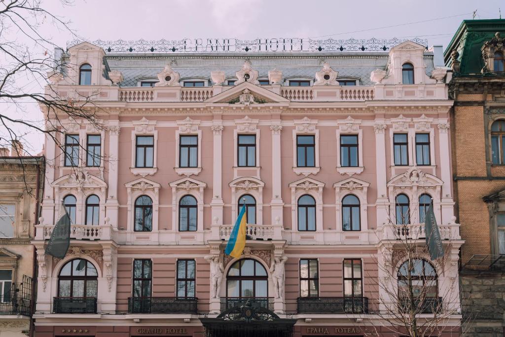 ein rosafarbenes Gebäude mit einer Flagge davor in der Unterkunft Grand Hotel Lviv Casino & Spa in Lwiw