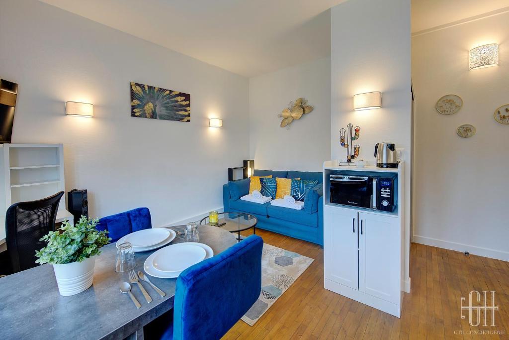 a living room with a table and a blue couch at L'Agapanthe - Proche Gare in Saint-Pierre-des-Corps