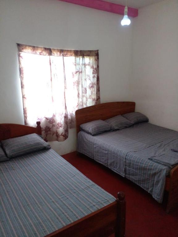 1 dormitorio con 2 camas y ventana en Green View In Nuwaraeliya en Nuwara Eliya