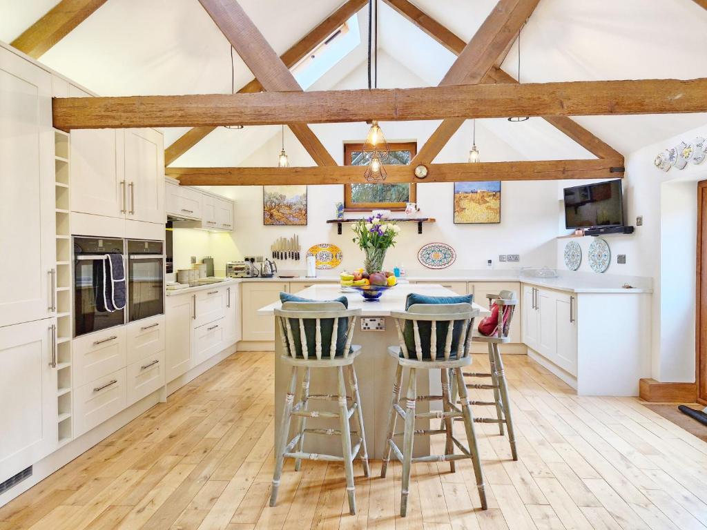 una cucina con armadi bianchi e un'isola con sgabelli da bar di Walnut Studio - Horsham a Horsham