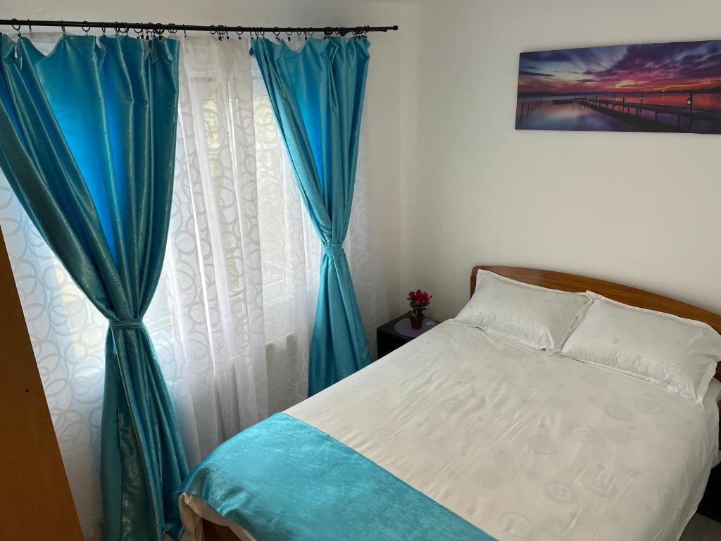 - une chambre dotée d'un lit avec des rideaux bleus et blancs dans l'établissement Iove Flat, à Tulcea