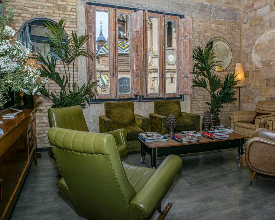 a living room with green chairs and a table at Apartamentos Basilicus in Zaragoza