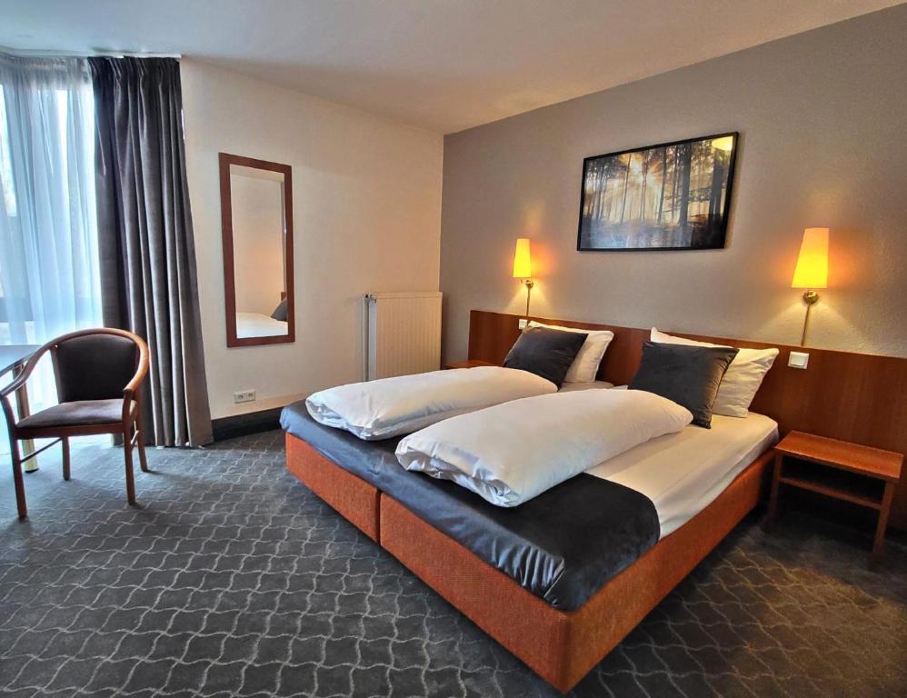 ein Hotelzimmer mit zwei Betten und einem Stuhl in der Unterkunft Concorde Hotel Ascot in Düsseldorf