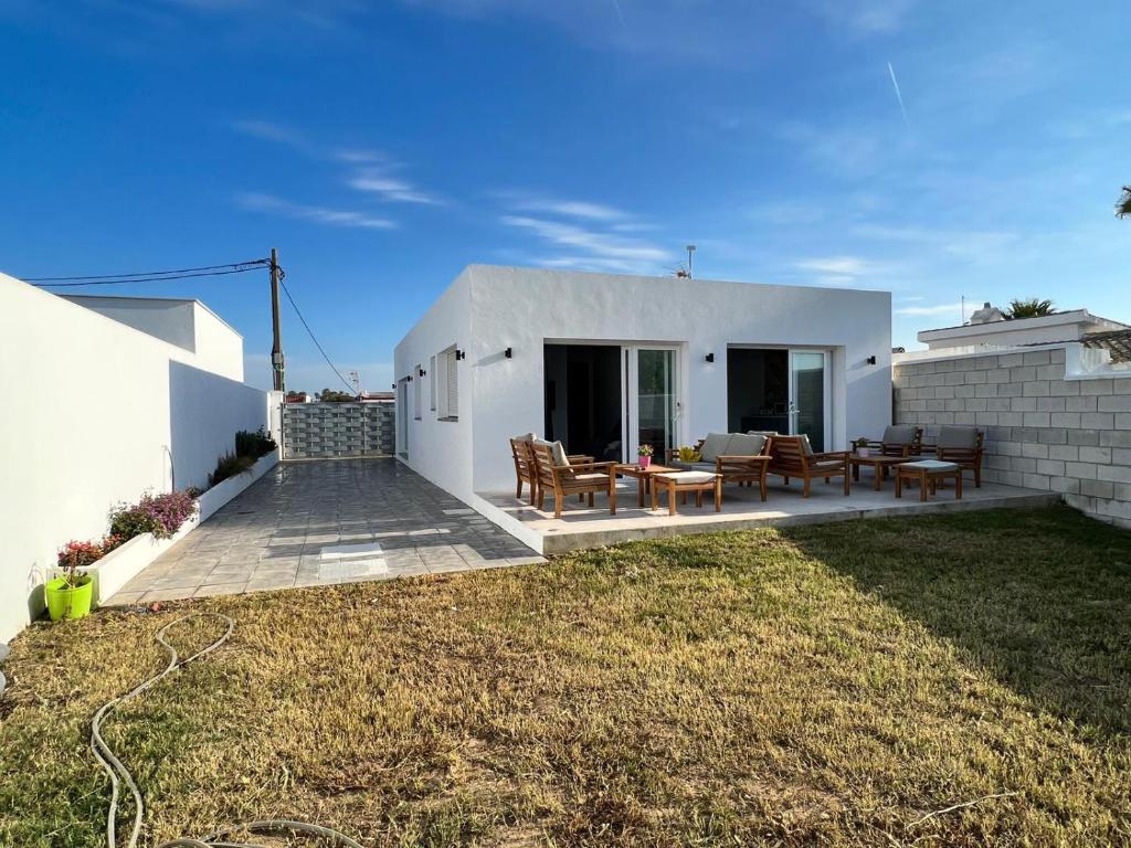 Casa blanca con patio con mesas y sillas en Agoodplan Aitana Playa El Palmar, en El Palmar