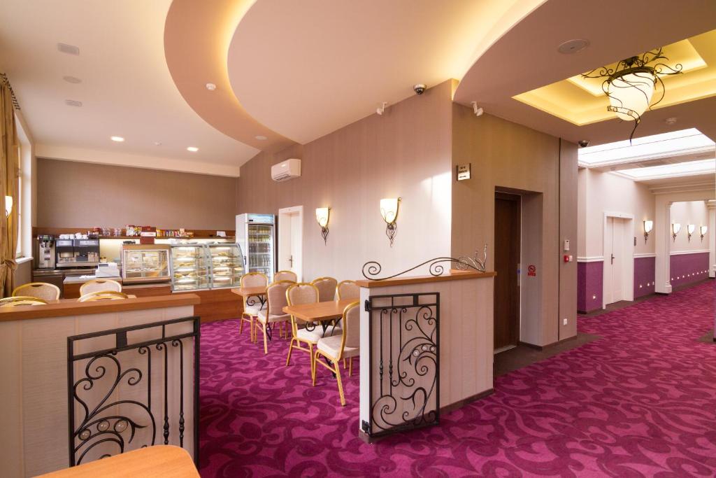 a restaurant with a bar and tables and chairs at Hotel Dvorana in Karlovy Vary