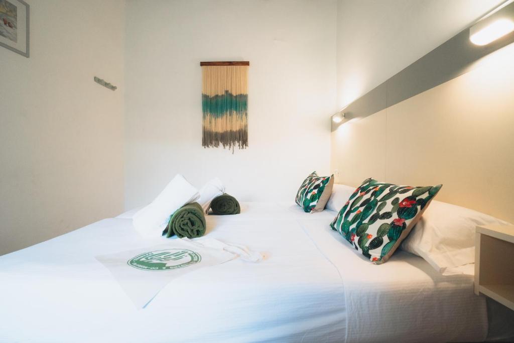 uma cama com lençóis brancos e almofadas em Cactus Hostel em San Sebastián de la Gomera
