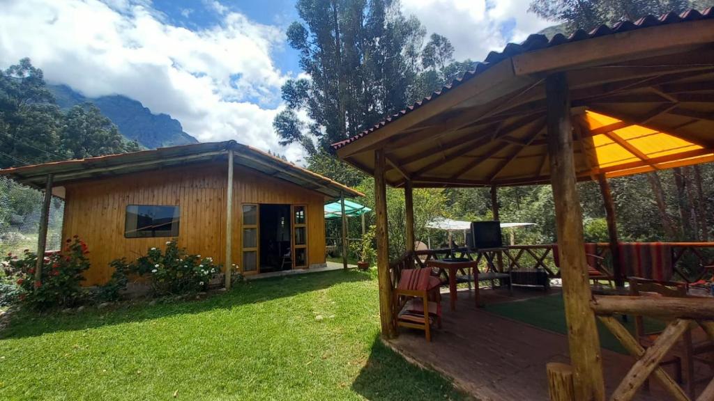 a log cabin with a table and chairs in the yard at Eco Lodge Cabañas con Piscina in Urubamba