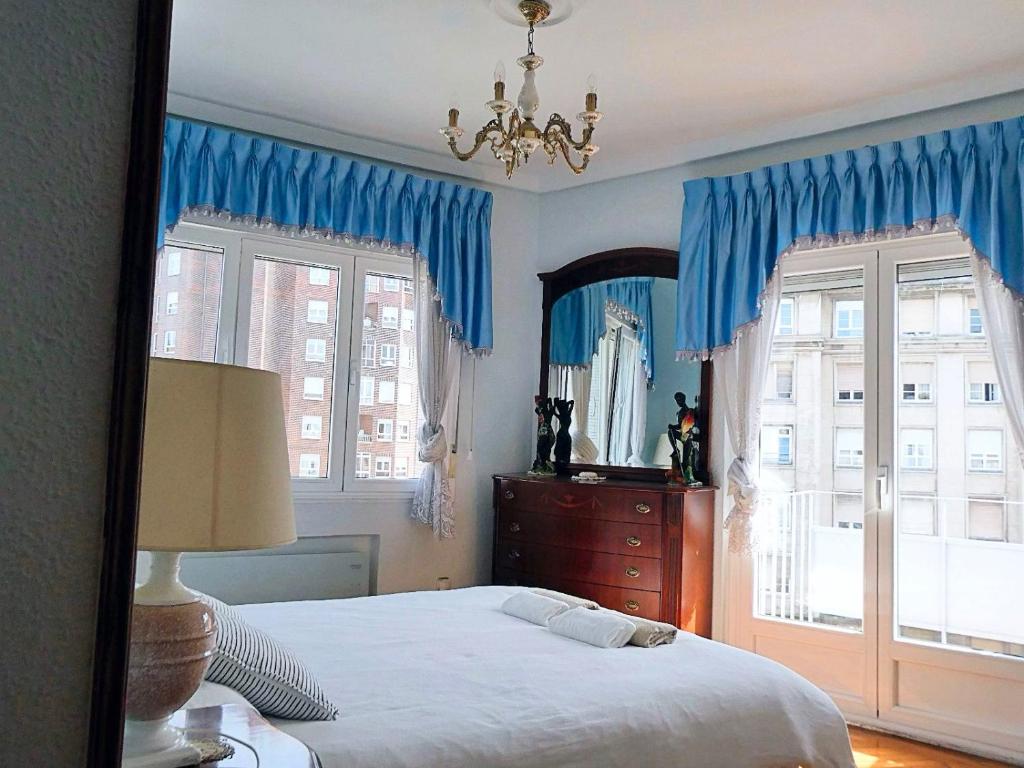 een slaapkamer met blauwe gordijnen, een bed en een raam bij Amplio y céntrico apartamento en Avilés by beBalmy in Avilés