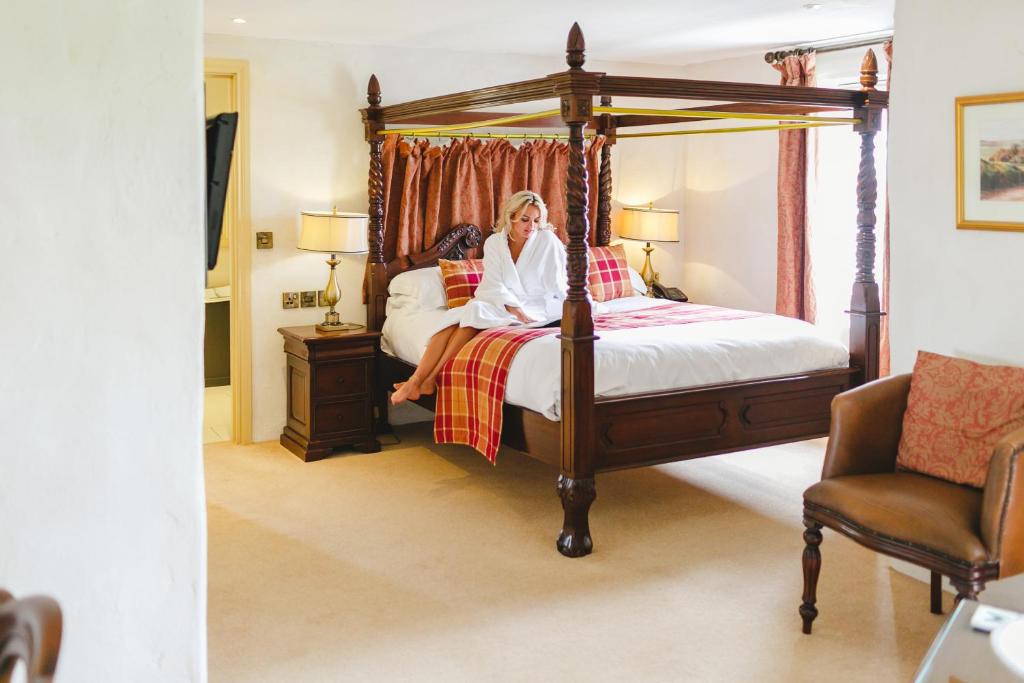 a woman sitting on a bed in a bedroom at Bushmills Inn Hotel & Restaurant in Bushmills