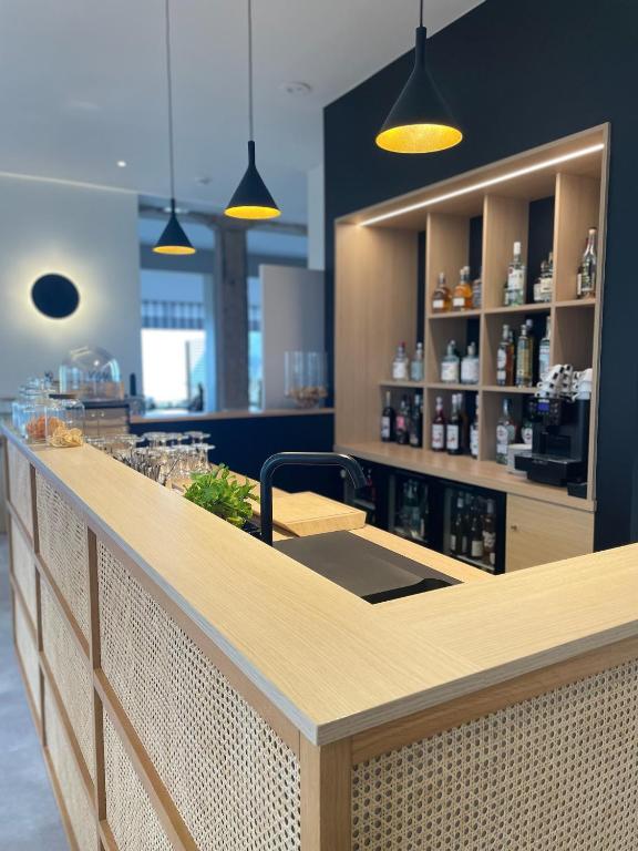 a bar in a restaurant with a counter with glasses at Hôtel Les Costans, The Originals Relais in Perros-Guirec