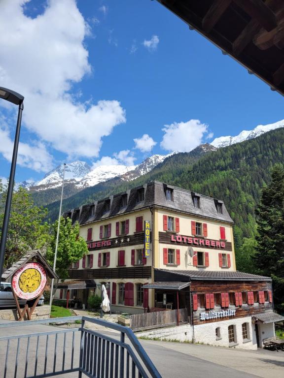 un hotel en las montañas con un reloj delante en Lötschberg en Kippel