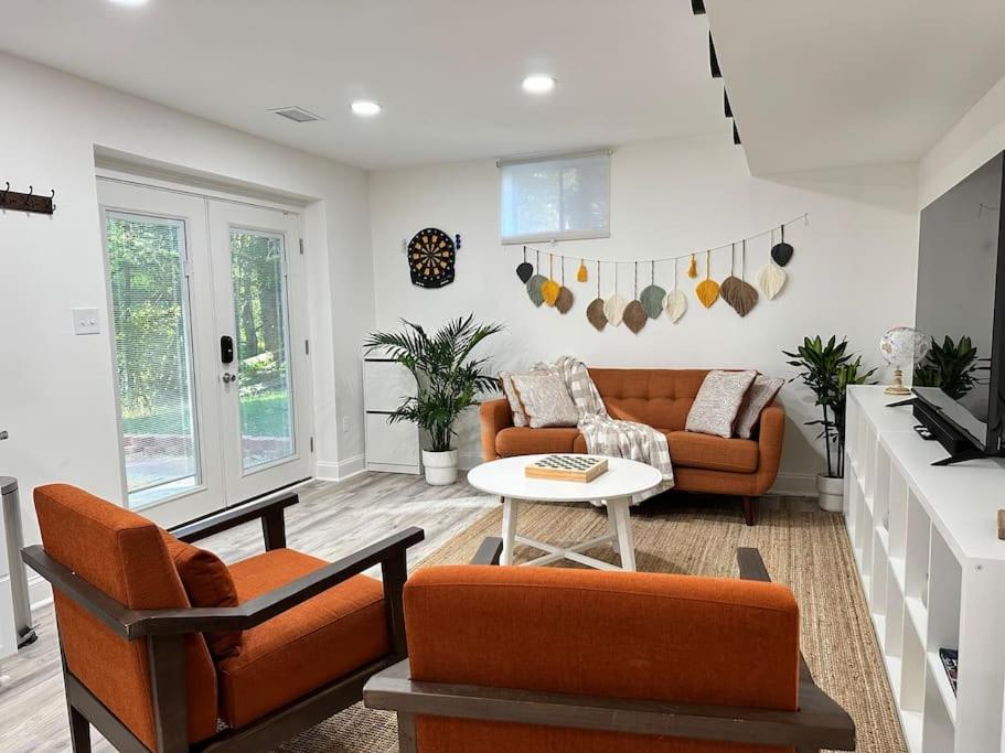 a living room with orange chairs and a table at Garden's Grace: Whispers in Silver Spring