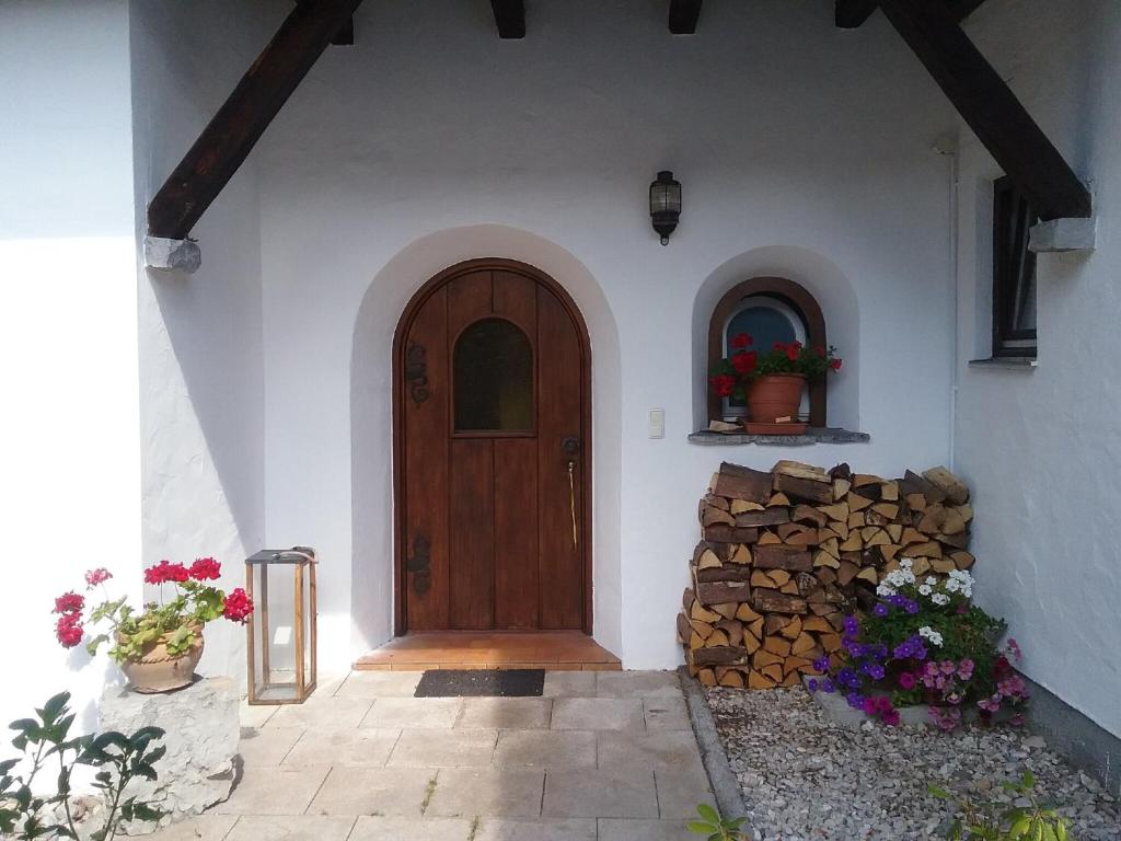 dom z drewnianymi drzwiami i stosem kłód w obiekcie Landhaus Lucia 2 w mieście Oberau