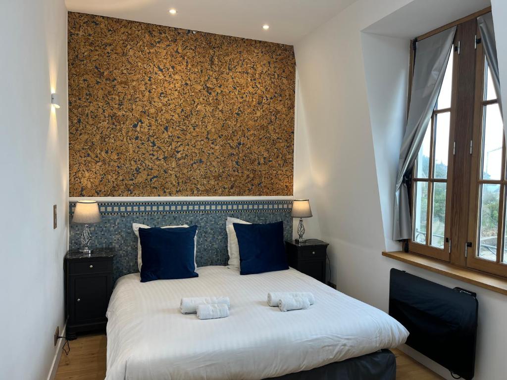 una camera da letto con un grande letto con cuscini blu di Le Royal XIX Dinard vue mer luxe a Dinard