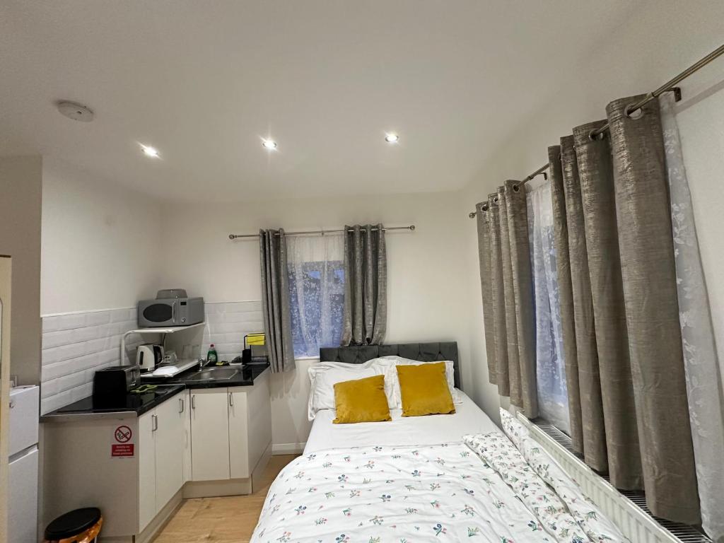 Dormitorio pequeño con cama con almohadas amarillas en 2nd Studio Flat With Great Views in Keedonwood Road With Private Kitchenette and shared bathroom en Bromley