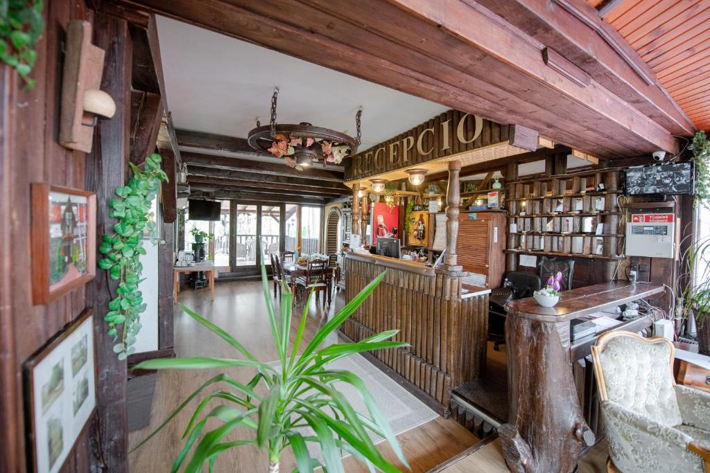 een restaurant met een bar en een plant in een kamer bij Hotel Barbizon in Nyíregyháza