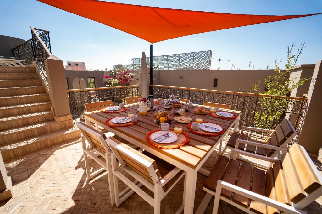 a wooden table on a balcony with an orange umbrella at Riad Oscaroi in Marrakesh