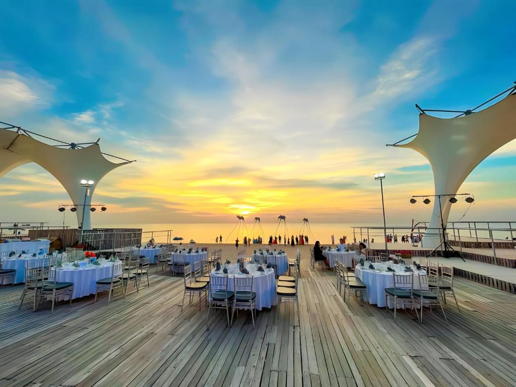 - un restaurant sur la plage avec des tables et des chaises blanches dans l'établissement Sunset Sanato Resort & Villas, à Duong Dong