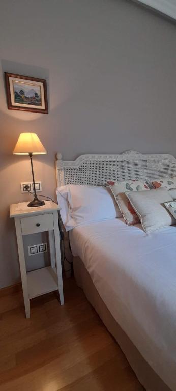 a bedroom with a bed and a table with a lamp at Gestiona2R - Apartamento en el casco antiguo Llanisco in Llanes
