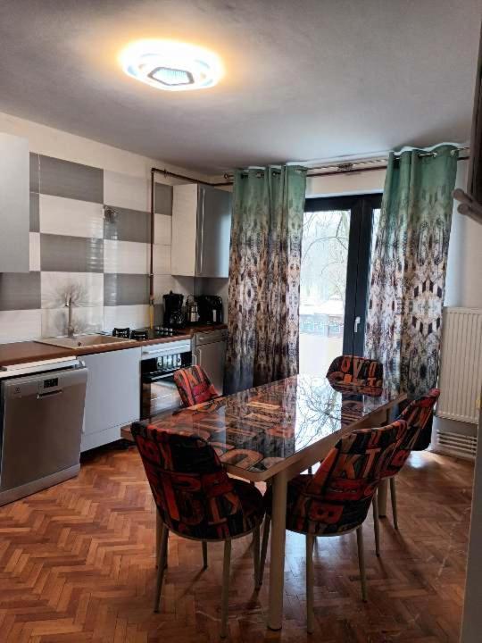 a kitchen with a table and chairs and a kitchen with a window at Apartament ANA in Carei