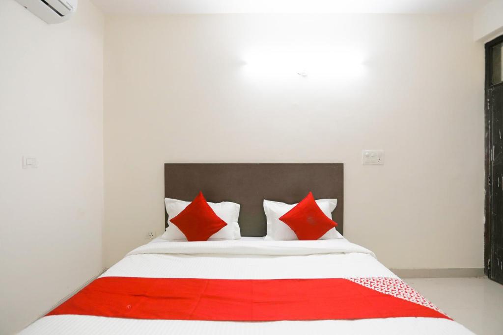 a bedroom with a bed with red and white pillows at OYO Flagship 61722 Rajmahal Residency Hotel in Bhiwadi