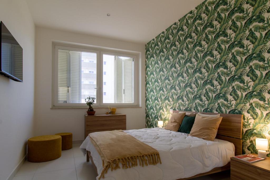 1 dormitorio con 1 cama grande y pared verde en Sky Suite Green Pomezia, en Pomezia