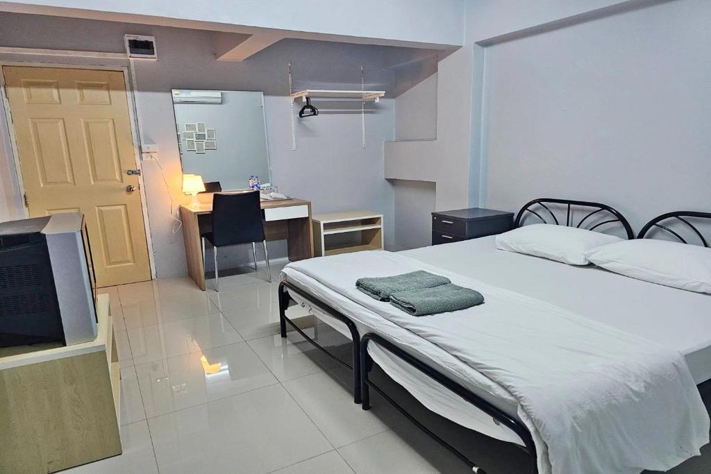 una camera con letto, scrivania e TV di Toucan Bed and Cafe a Samutprakarn