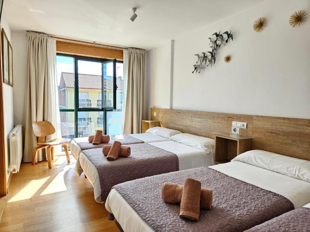 a hotel room with three beds and a window at PENSION ROSELLA in O Pedrouzo