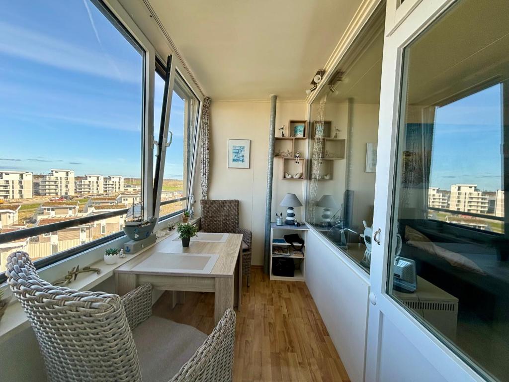 una stanza con un tavolo, sedie e finestre di Ferienwohnung Fördeblick 7605 in Marina Wendtorf a Wendtorf