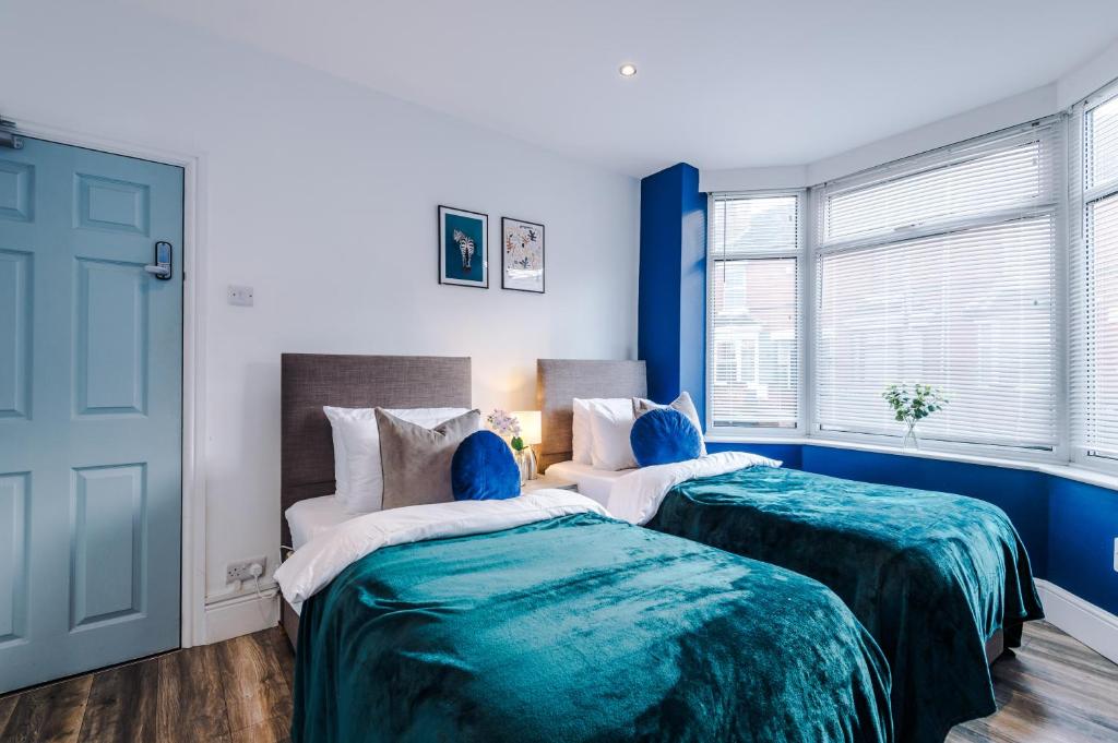 two beds in a room with blue walls at Fantastic Five Bedroom House By PureStay Short Lets & Serviced Accommodation South Yorkshire With Parking in Bentley