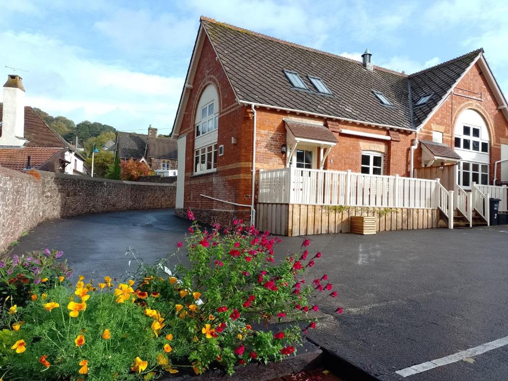 a brick house with flowers in a parking lot at Finest Retreats - Lower School Cottages in Minehead